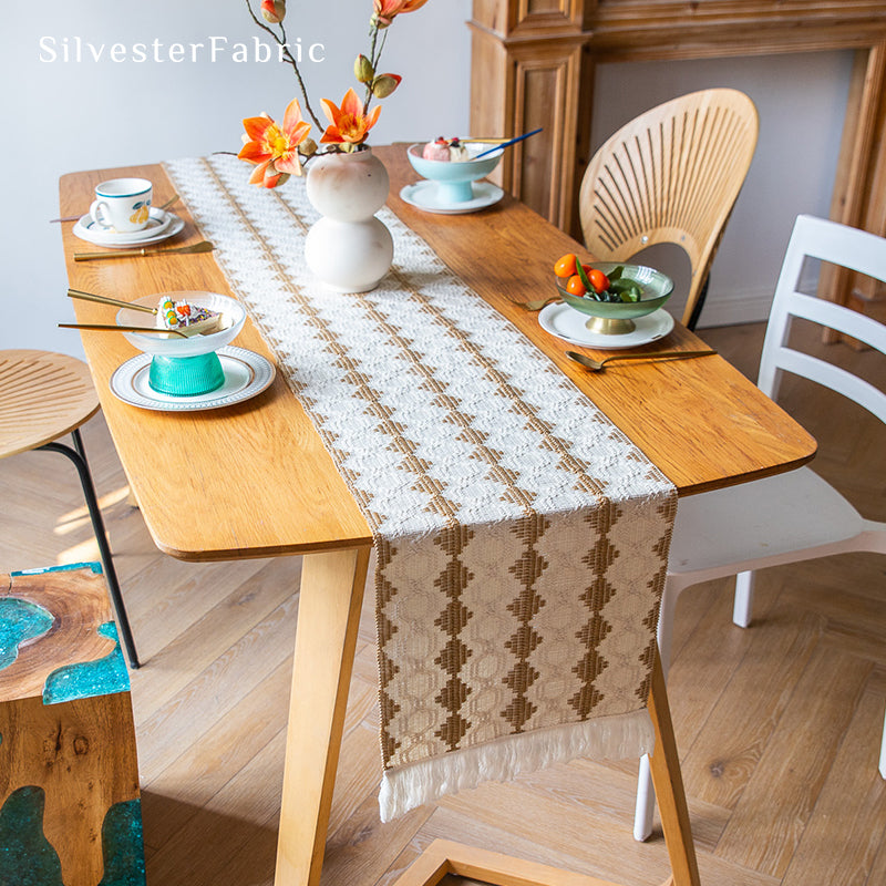 A beige boho crochet table runner on the table