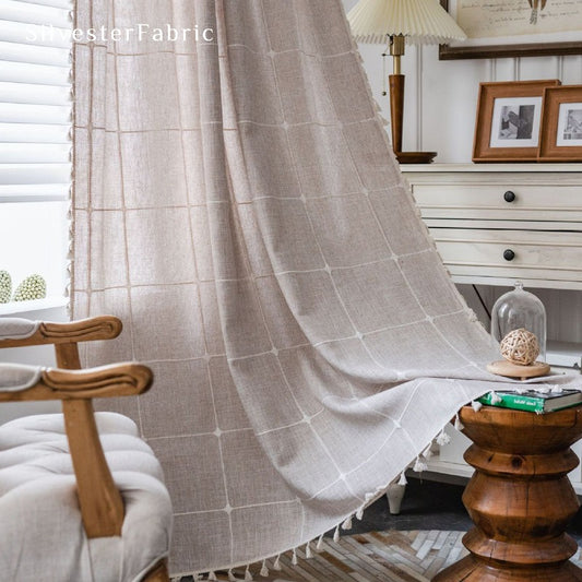 Embroidered plaid beige curtains hang in the living room window