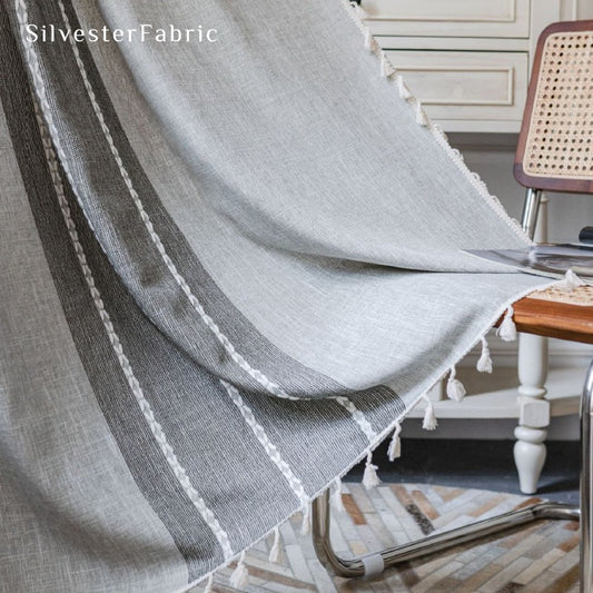 Embroidered striped light grey curtains hanging over bedroom window