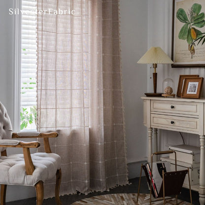 Embroidered plaid beige curtains hang in the living room window