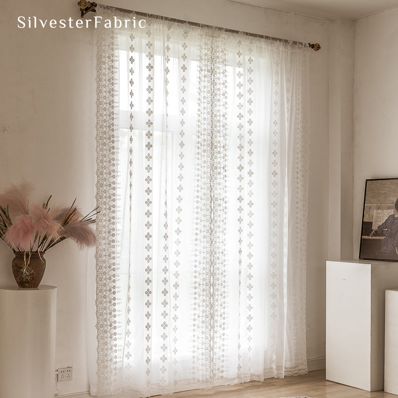 Floral white sheer curtains hanging in bedroom window