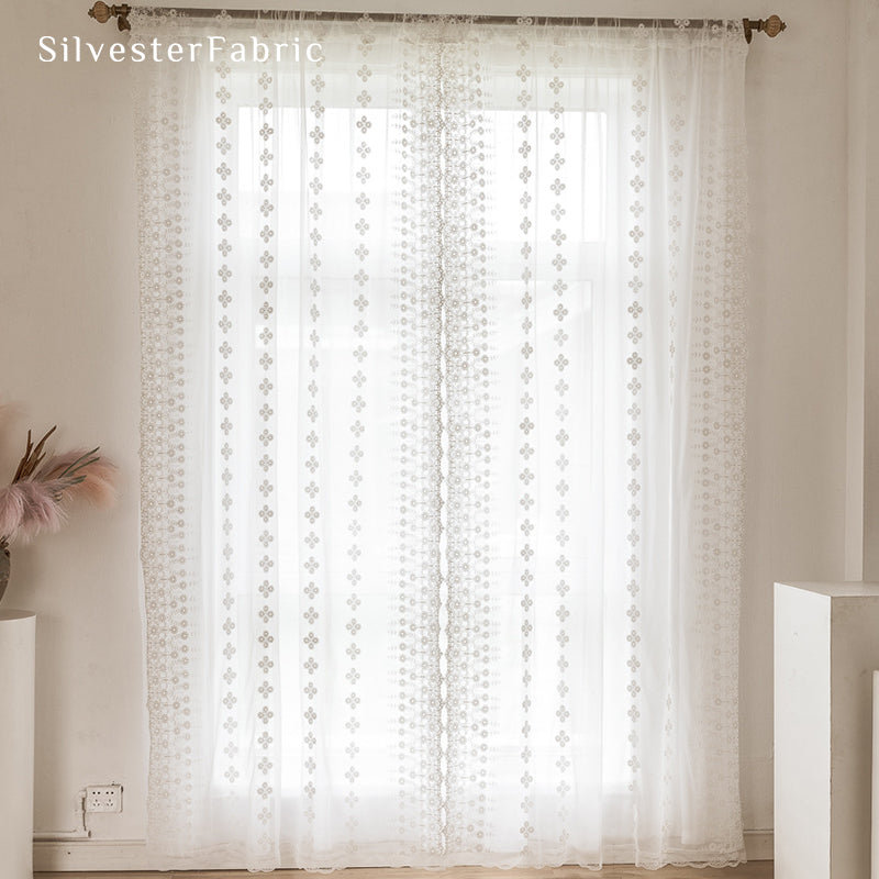 Floral white sheer curtains hanging in bedroom window