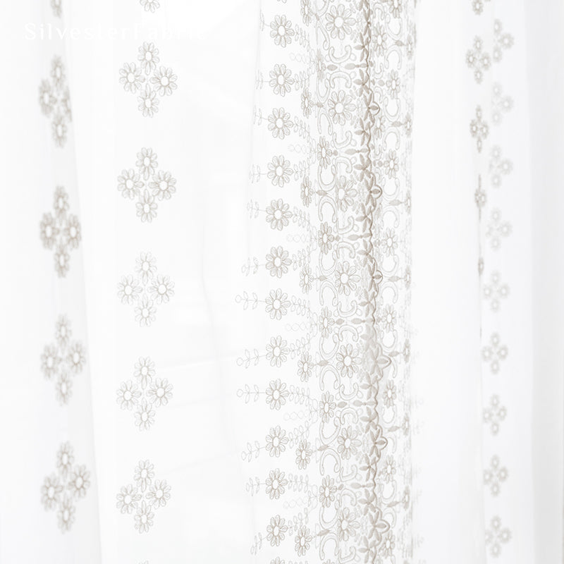 Floral white sheer curtains hanging in bedroom window