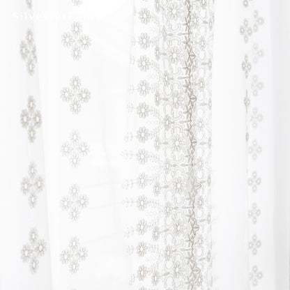 Floral white sheer curtains hanging in bedroom window