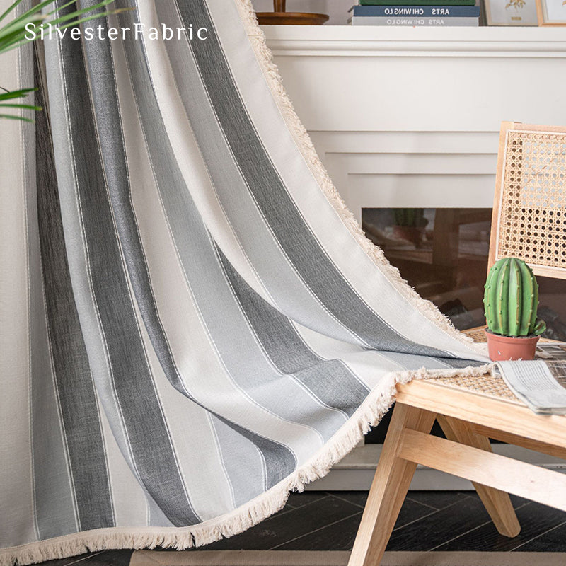 Gray striped color block curtains hang over the bedroom window .