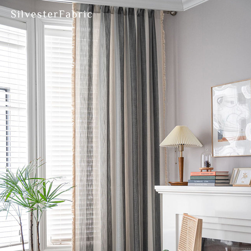 Gray striped color block curtains hang over the bedroom window .