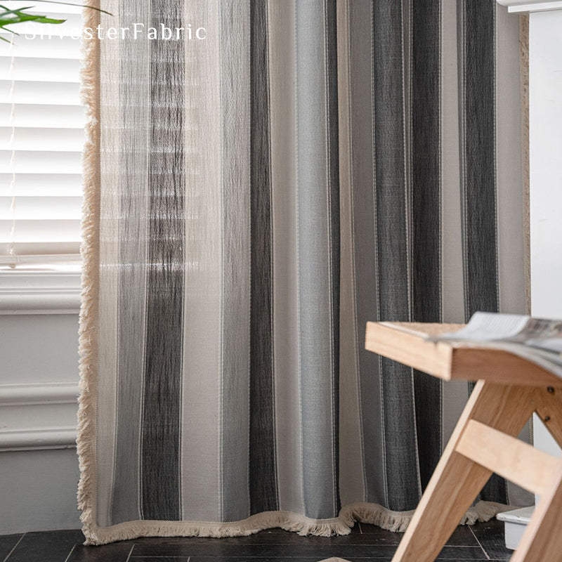 Gray striped color block curtains hang over the bedroom window .