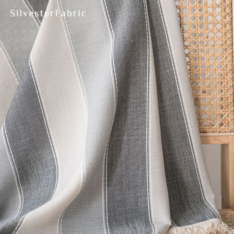 Gray striped color block curtains hang over the bedroom window .