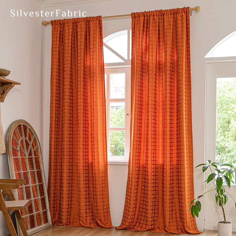 Orange jacquard farmhouse curtain hanging in window