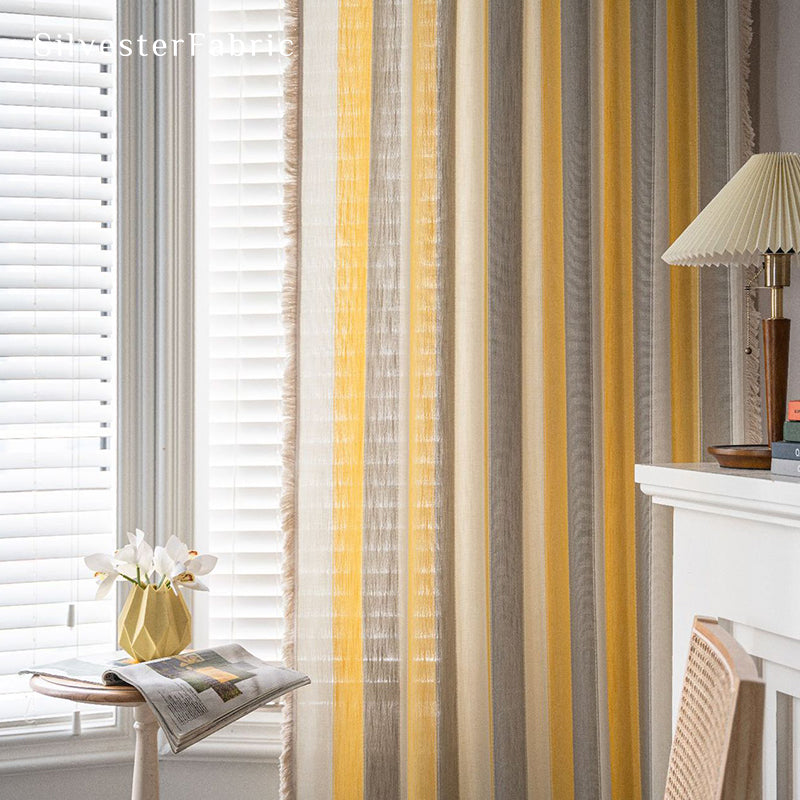 Yellow striped color block curtains hang over the wide bedroom window