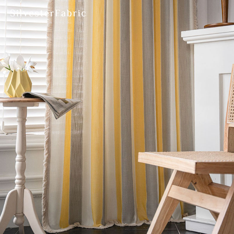 Yellow striped color block curtains hang over the wide bedroom window