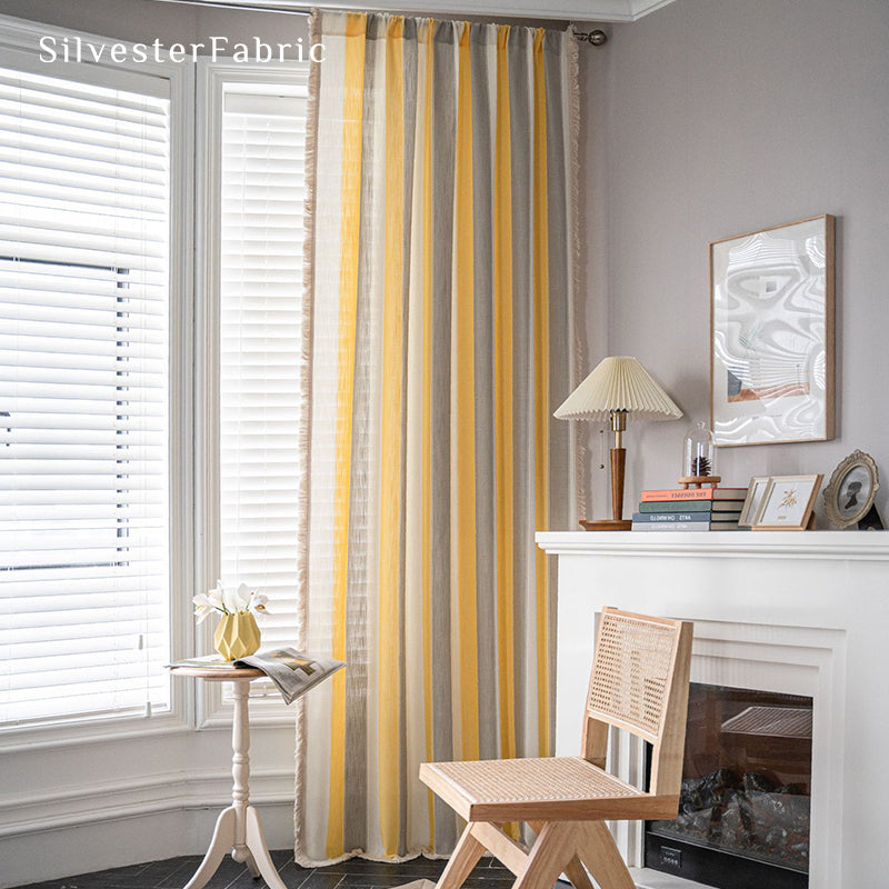 Yellow striped color block curtains hang over the wide bedroom window