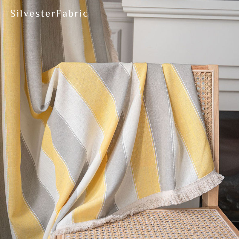 Yellow striped color block curtains hang over the wide bedroom window