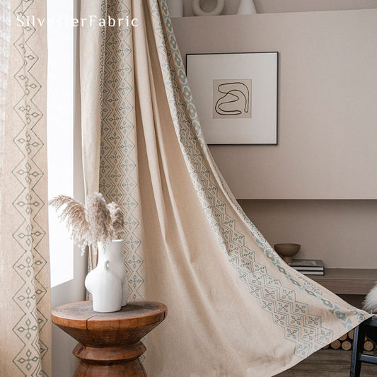 Beige linen curtains with blue embroidery on both sides hang over the windows