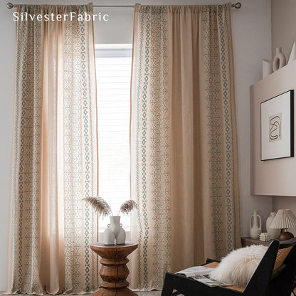 Beige linen curtains with blue embroidery on both sides hang over the windows