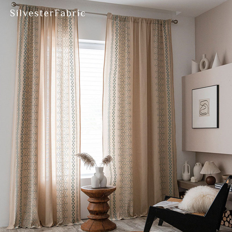 Beige linen curtains with blue embroidery on both sides hang over the windows