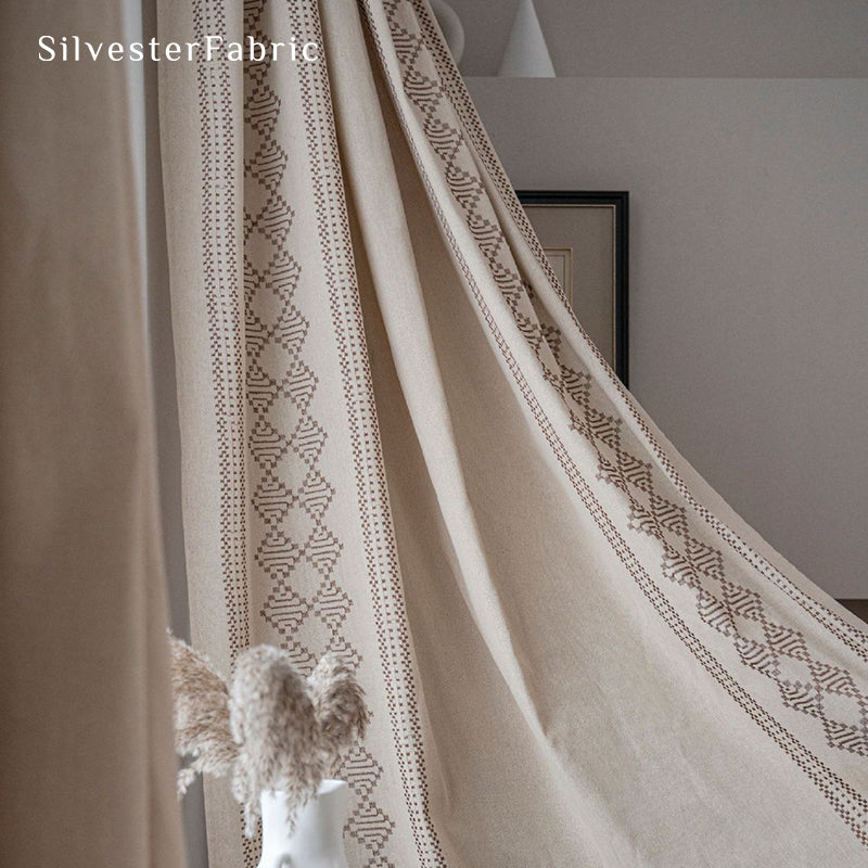 Beige linen curtains with embroidery on both sides hang in the window