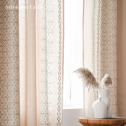 Beige linen curtains with blue embroidery on both sides hang over the windows