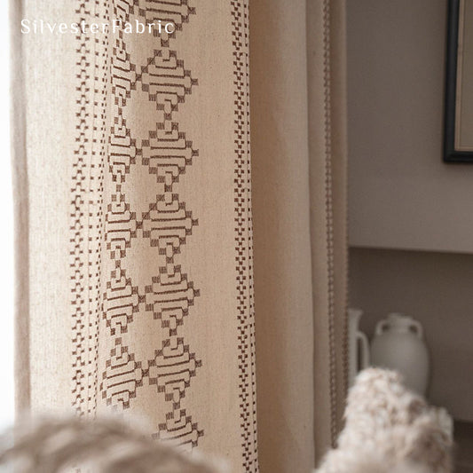 Beige linen curtains with embroidery on both sides hang in the window