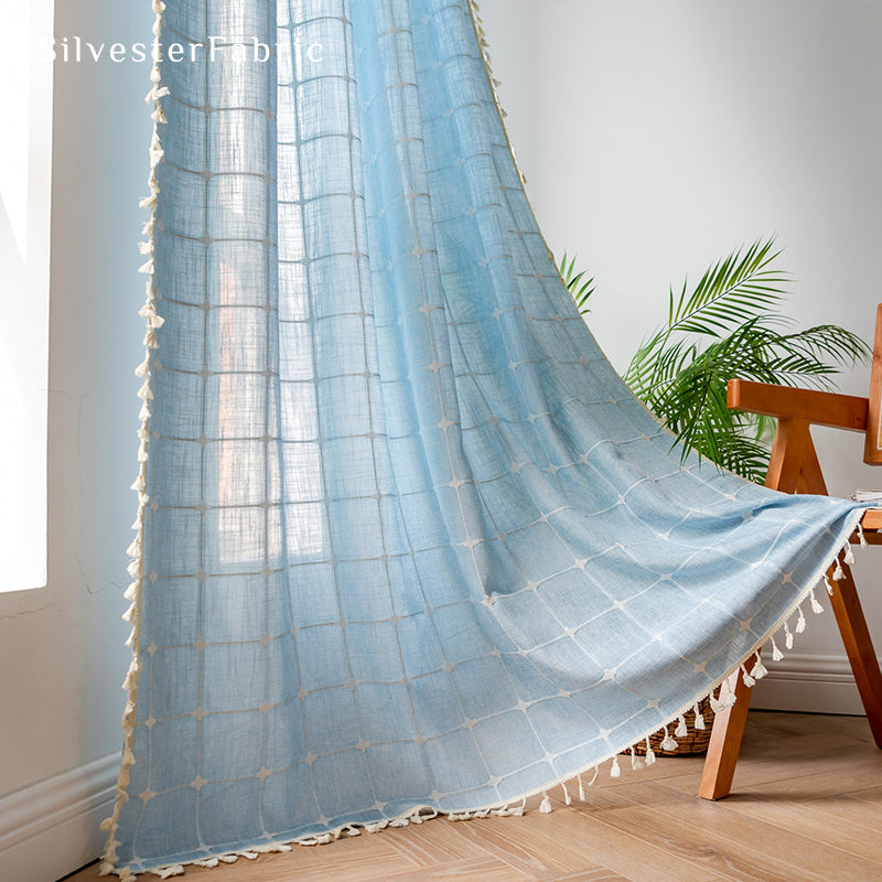 Embroidered plaid light blue curtains hanging in the bedroom window