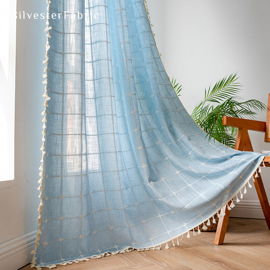 Embroidered plaid light blue curtains hanging in the bedroom window