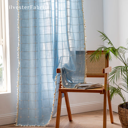 Embroidered plaid light blue curtains hanging in the bedroom window