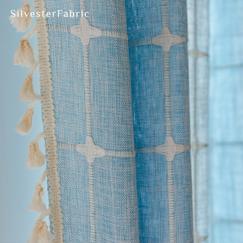 Embroidered plaid light blue curtains hanging in the bedroom window