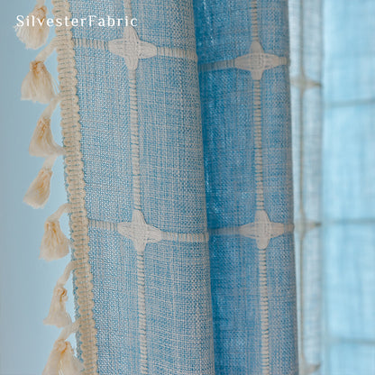 Embroidered plaid light blue curtains hanging in the bedroom window