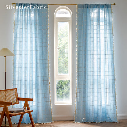 Embroidered plaid light blue curtains hanging in the bedroom window