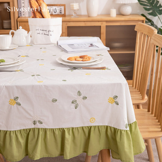 A white french floral embroidered rectangle tablecloth covers the table