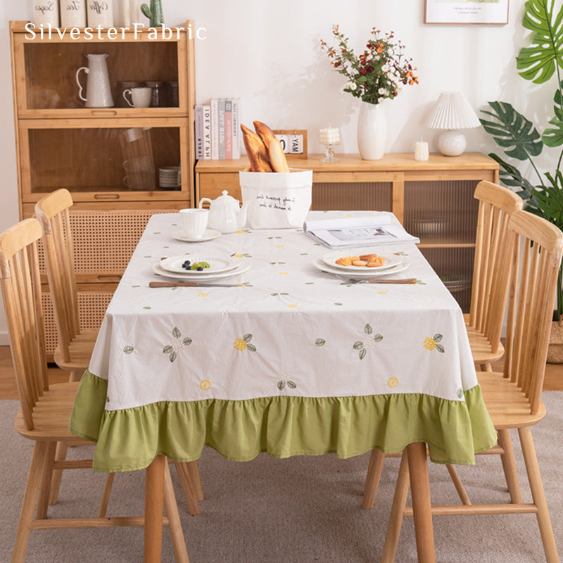 A white french floral embroidered rectangle tablecloth covers the table