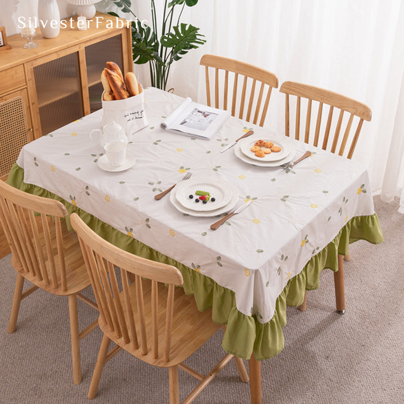 A white french floral embroidered rectangle tablecloth covers the table