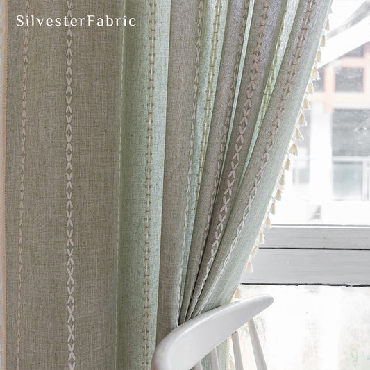 Sage green striped embroidered curtains hanging in bedroom window