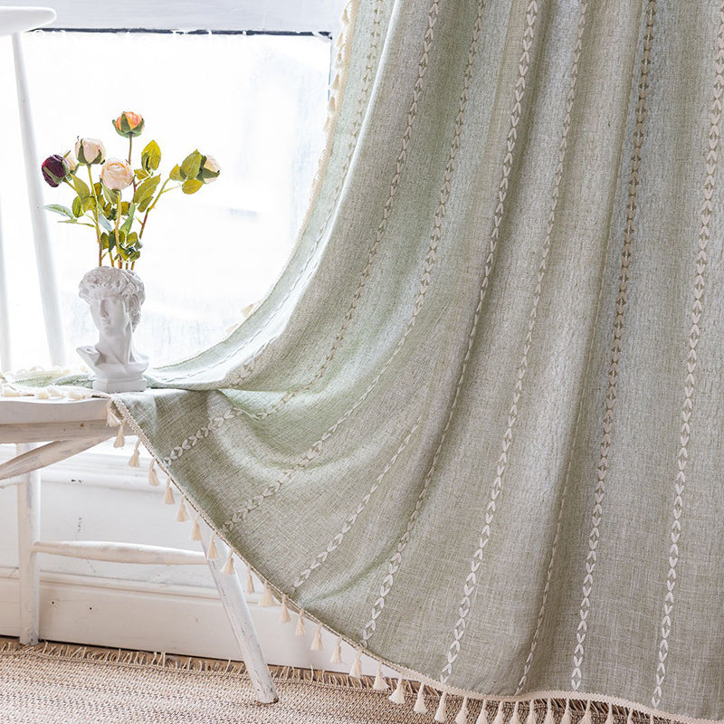 Sage green striped embroidered curtains hanging in bedroom window