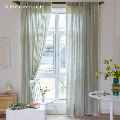 Sage green striped embroidered curtains hanging in bedroom window