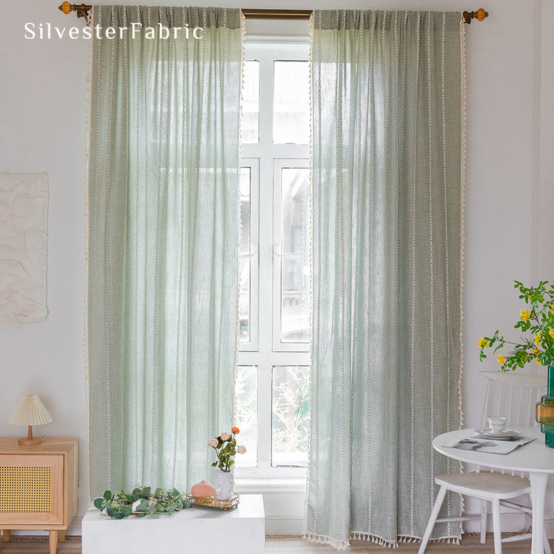 Sage green striped embroidered curtains hanging in bedroom window