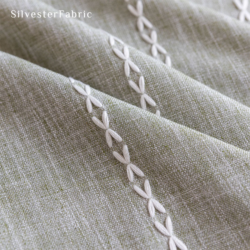 Sage green striped embroidered curtains hanging in bedroom window