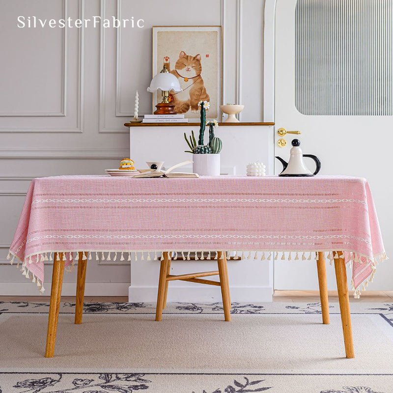 Striped embroidered pink tablecloth covers the table