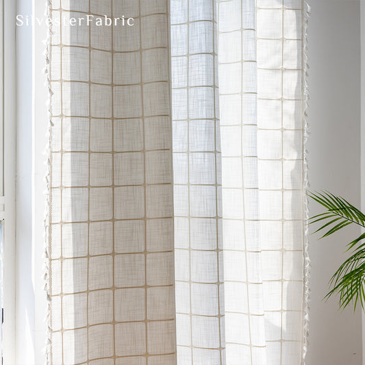 Embroidered plaid white curtains hang in the living room window