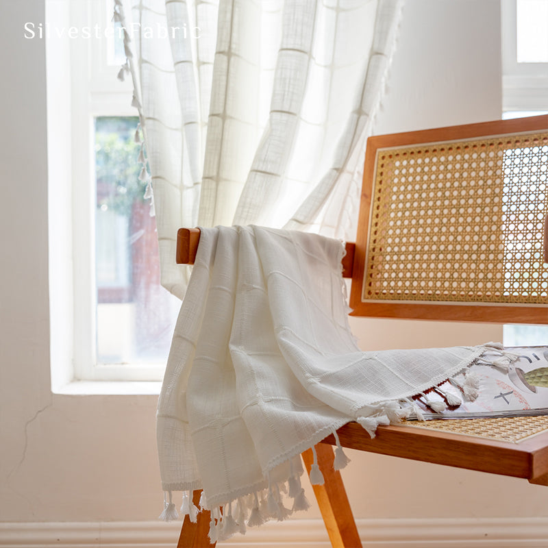 Embroidered plaid white curtains hang in the living room window