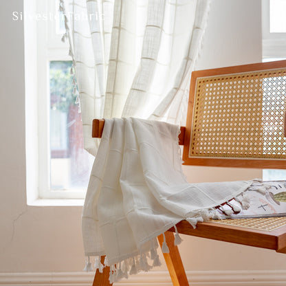 Embroidered plaid white curtains hang in the living room window