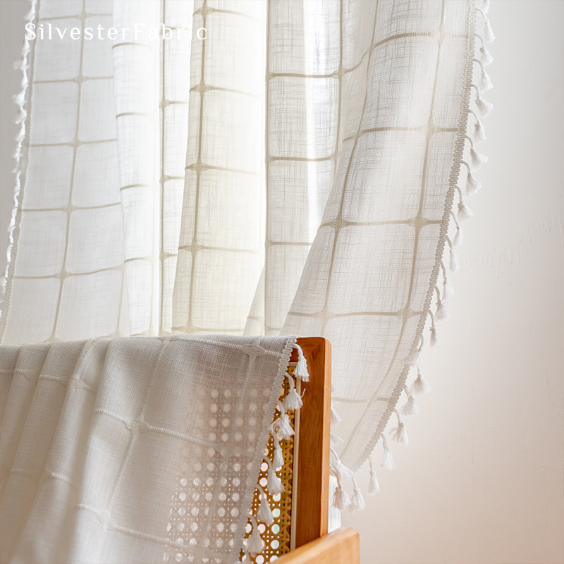 Embroidered plaid white curtains hang in the living room window