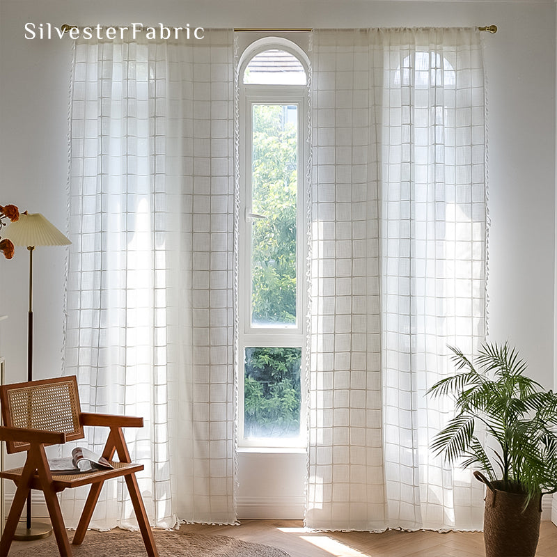 Embroidered plaid white curtains hang in the living room window