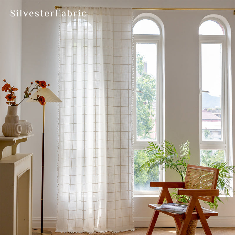 Embroidered plaid white curtains hang in the living room window