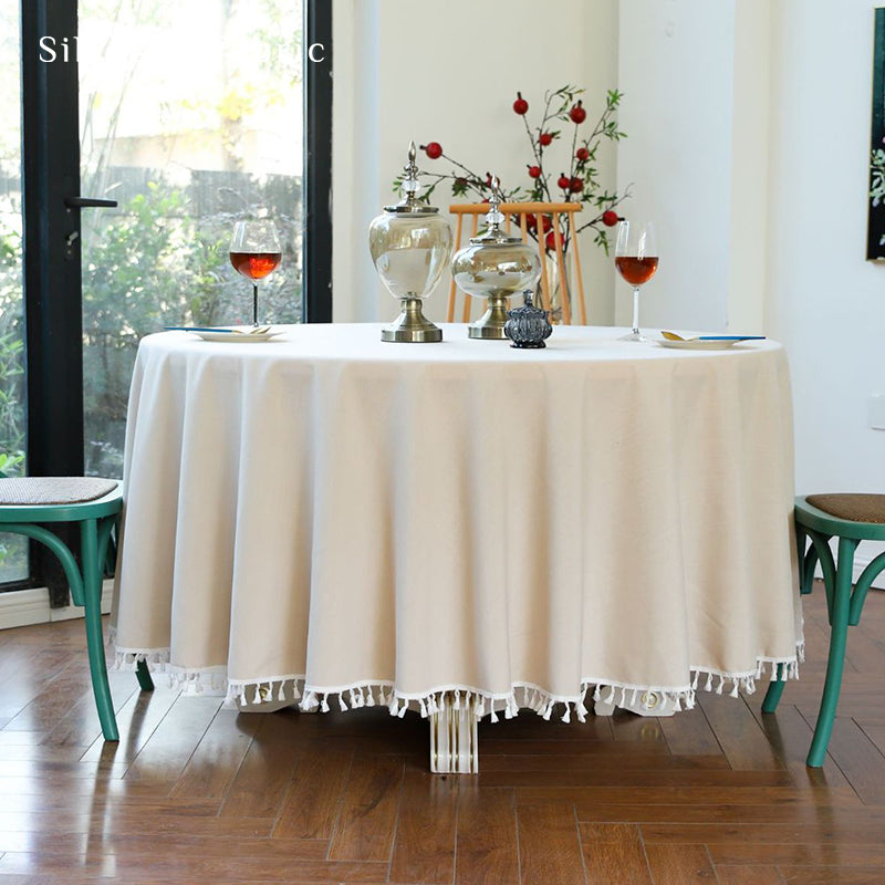 A beige round tablecloth covers a large round table