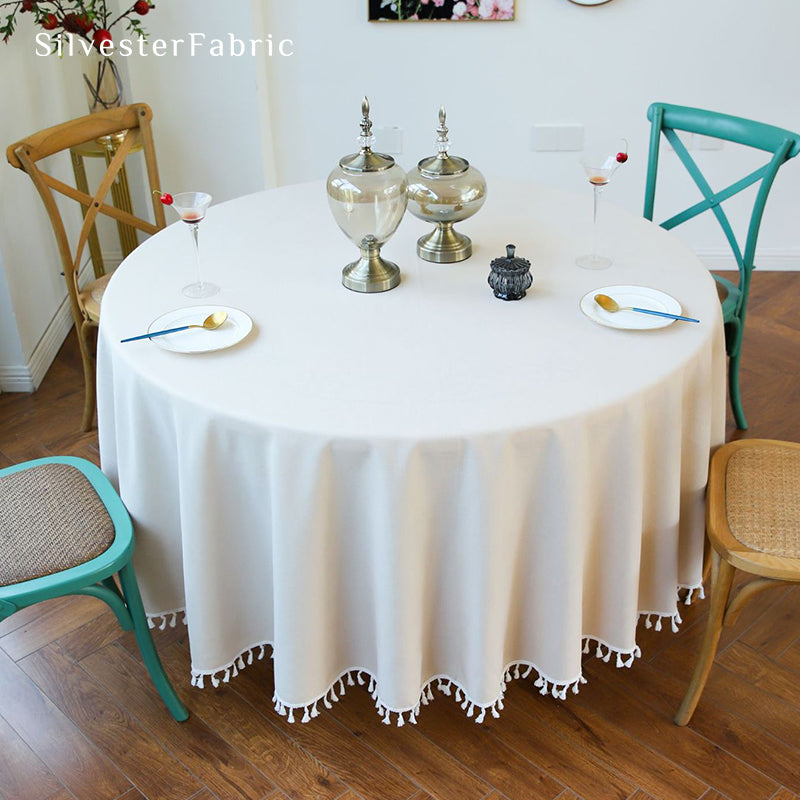 A beige round tablecloth covers a large round table