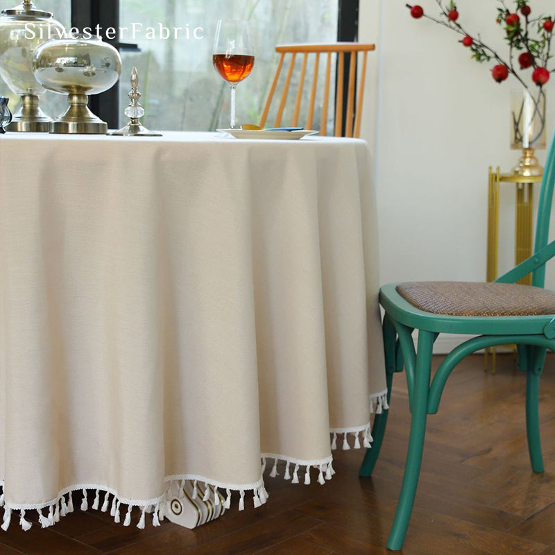 A beige round tablecloth covers a large round table