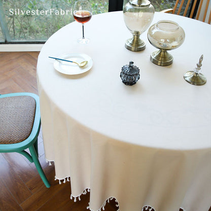 A beige round tablecloth covers a large round table