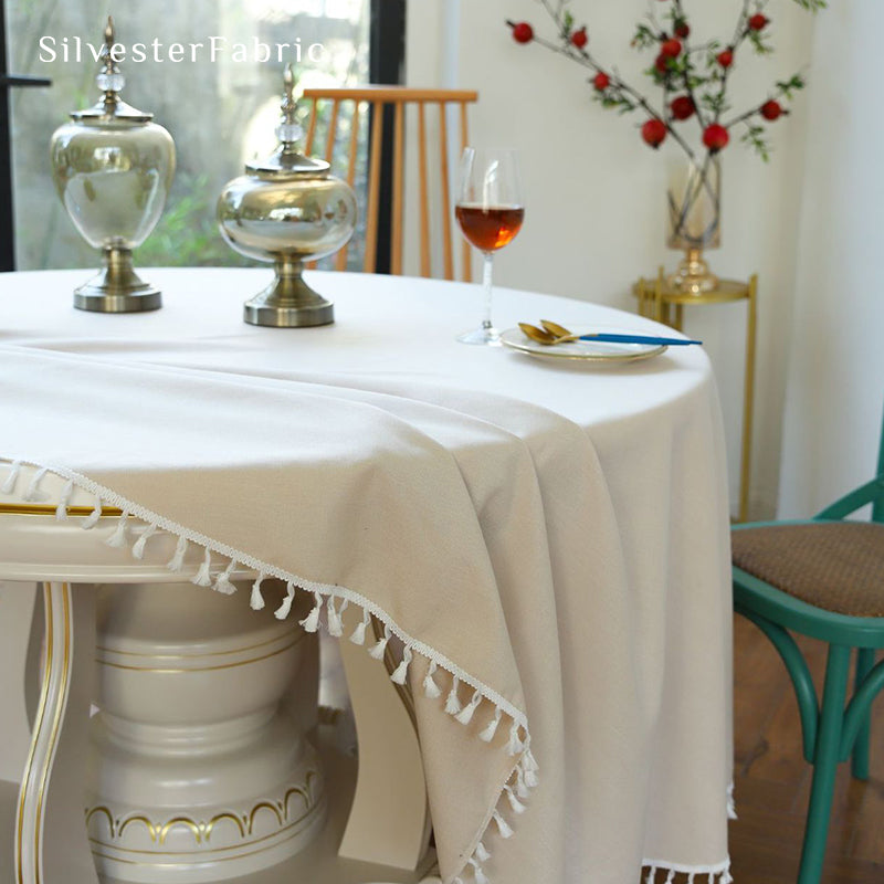 A beige round tablecloth covers a large round table